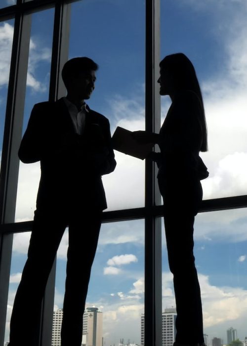 Silhouettes of two business people discussing in the office.